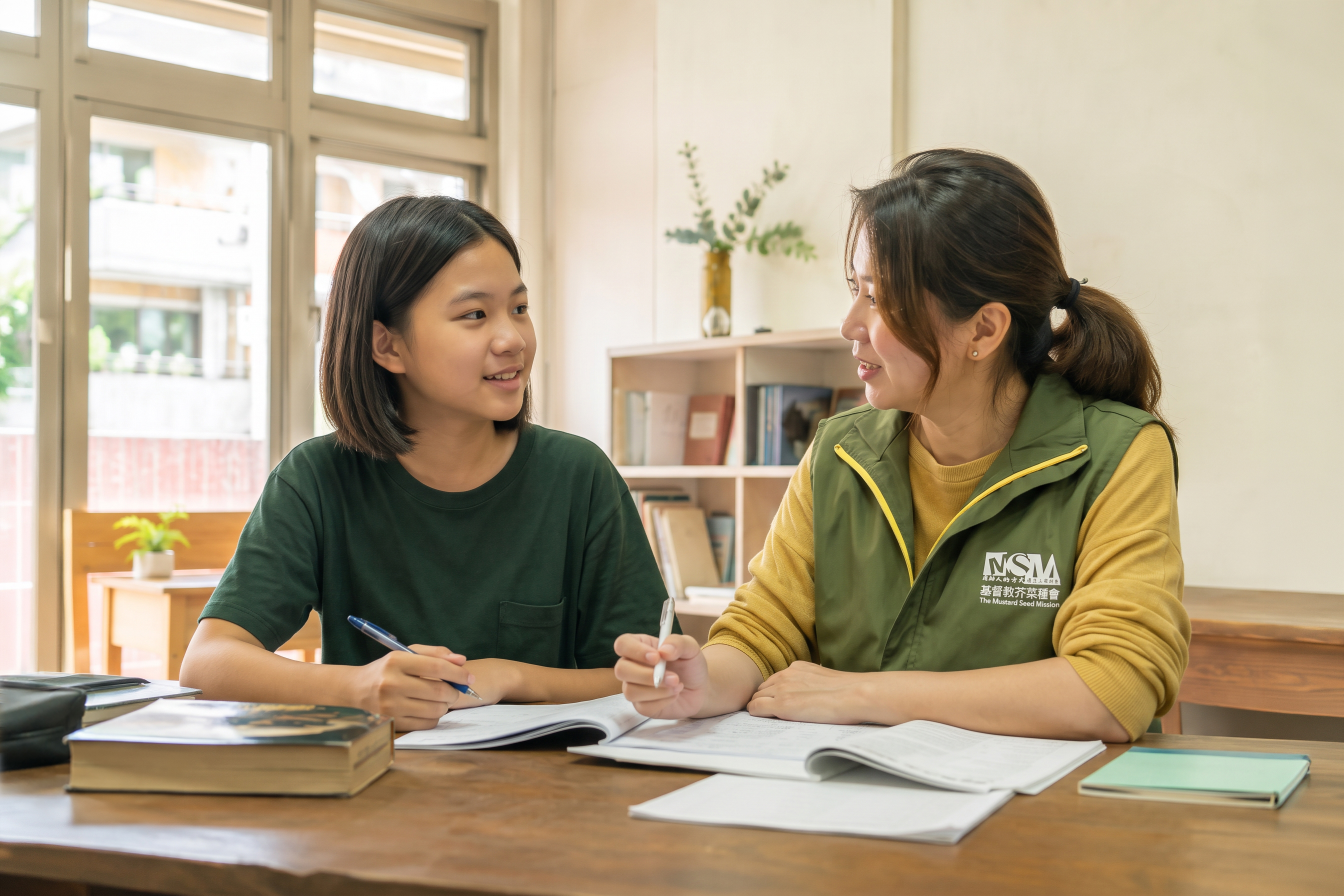 Illustrative photograph of a Taiwanese student reviewing schoolwork with an adult mentor