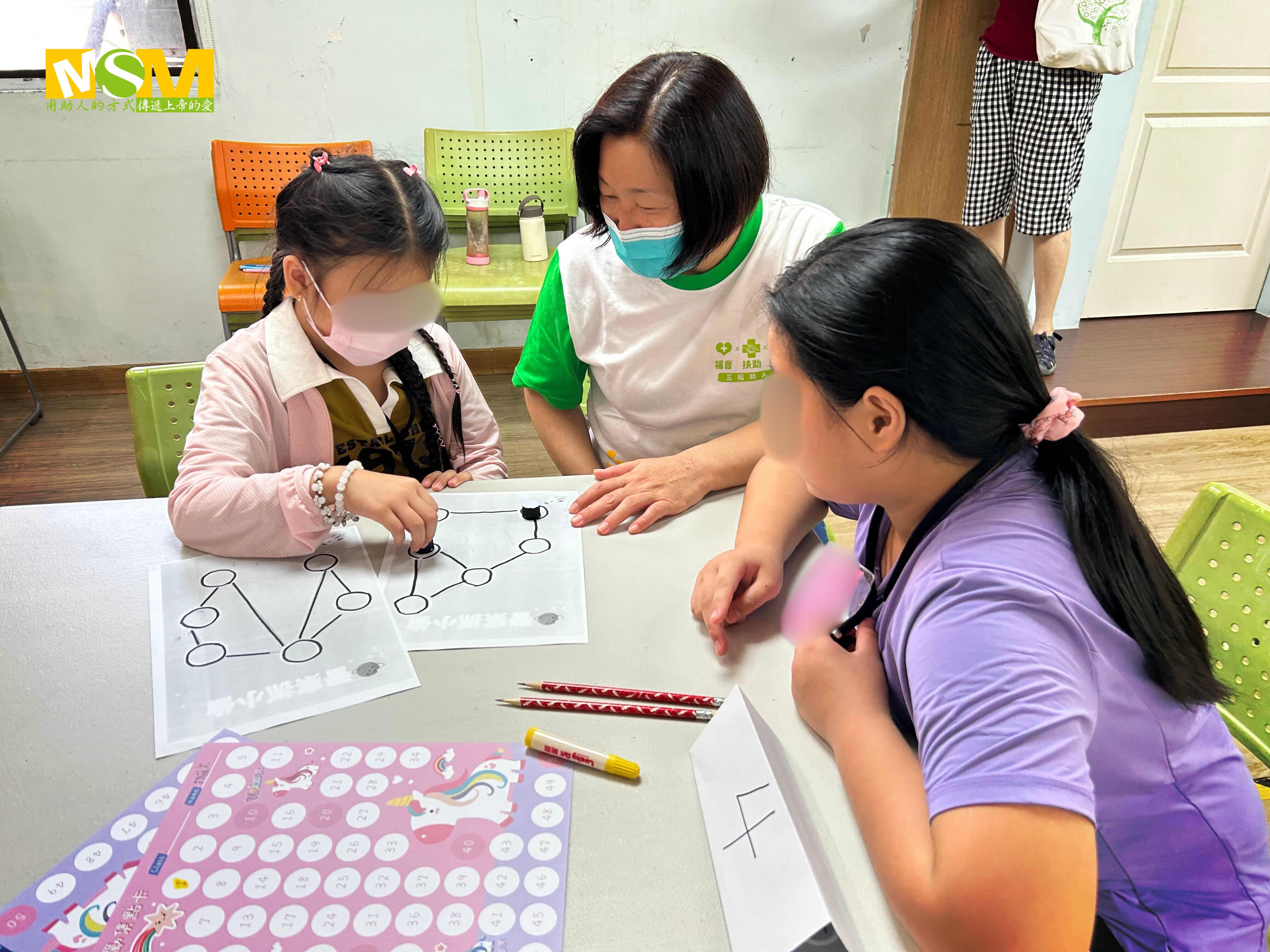 受培力的社區助人志工（中）成為困難家庭重要的陪伴者，圖為陪伴認養童玩數學。