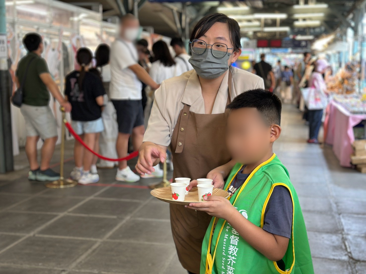 怡靜（左）帶著兒子擔任市集小幫手，一起邀請民眾試飲「習得茶」，留下難忘的親子回憶。