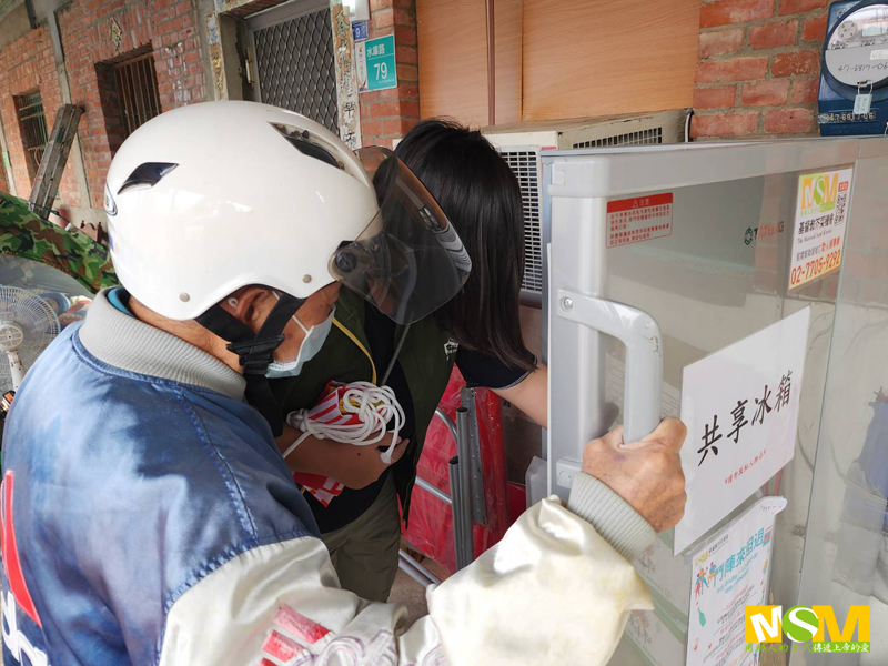 安置的災民取用共享冰箱的冷凍料理包